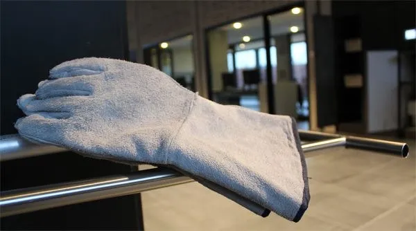 A heat-resistant glove resting on the steel rail of a cremator